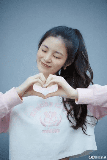 h4，女孩儿拍照时抬手比心超甜腻